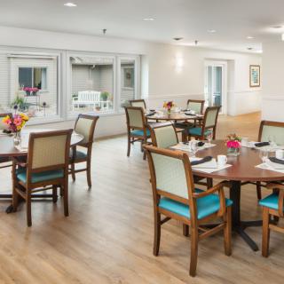 A modern dining area with neatly arranged tables and chairs on a wooden floor.
