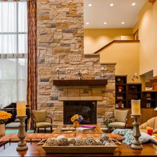 A cozy living room with a stone fireplace and high ceilings, featuring warm lighting and stylish decor.