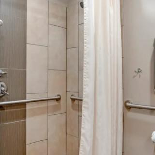 A bathroom shower area designed for accessibility, featuring tiled walls and safety grab bars.