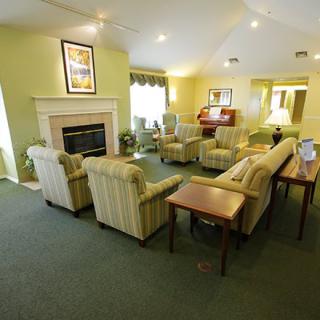A cozy living room with multiple couches and chairs arranged around a central fireplace.
