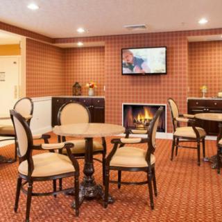 A cozy lounge area with tables, chairs, a fireplace, and a television.