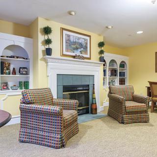 A cozy living room featuring a fireplace flanked by built-in bookshelves and two patterned armchairs.