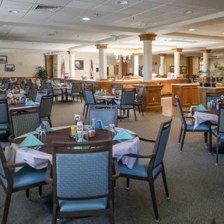 A spacious dining room with neatly arranged tables and chairs, set up for service.