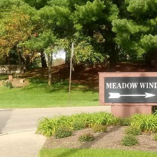 Entrance sign for Meadow Wind, surrounded by lush greenery.
