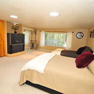 A spacious bedroom with a large bed, television, and ample natural light from the windows.