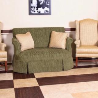 A living room setup featuring a green sofa with two beige pillows, flanked by two beige armchairs on a checkered tile floor.