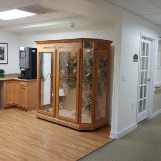 A reception area featuring a wooden glass display cabinet and office setting.