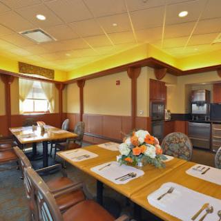 A cozy dining room featuring elegant wooden furniture, a tasteful table setting with flowers, and inviting warm lighting.