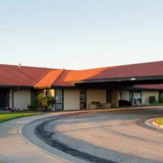 A building with a red roof and a circular driveway entrance in sunlight.
