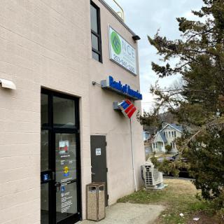 View of a storefront featuring a business sign and a flag.