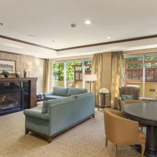 A spacious living room with elegant furniture, featuring a fireplace and large windows.