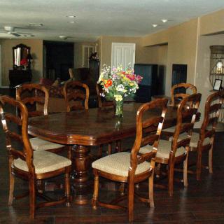 A spacious dining room with a large wooden table surrounded by elegant chairs and a floral arrangement centerpiece.
