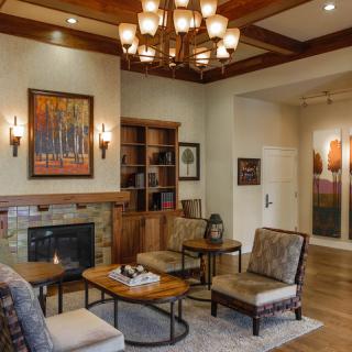 A cozy living room with elegant furnishings, a warm fireplace, and a grand chandelier.