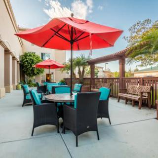 A sunny outdoor patio with red umbrellas and comfortable garden furniture.