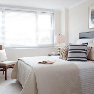 A modern minimalist bedroom filled with natural light, featuring a neatly made bed and stylish decor.