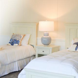 A cozy bedroom with twin beds adorned with decorative pillows and a stylish lamp on the nightstand.