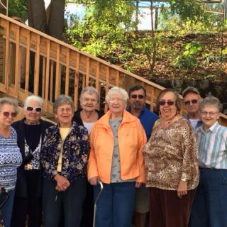 A group of seniors posing for a photo outdoors, dressed in casual clothing.