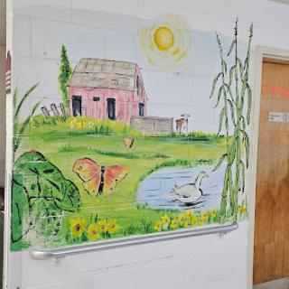 A vibrant mural depicting a serene rural landscape with a house, butterfly, and pond under the sun.