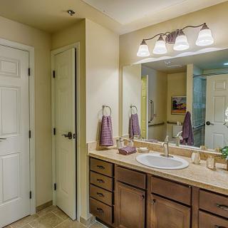 A well-lit bathroom with a large mirror and wooden vanity.