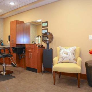 A cozy salon interior with a barber chair, vanity, and waiting area.