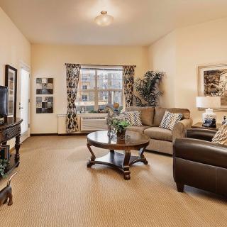 A cozy living room featuring a comfortable sofa set and a central coffee table, beautifully decorated with curtains and artwork.