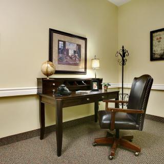 A well-organized office corner with a desk and chair, complemented by wall art and a lamp.