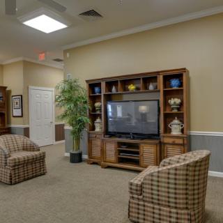 A cozy living room with a large television, comfortable seating, and thoughtful decor.