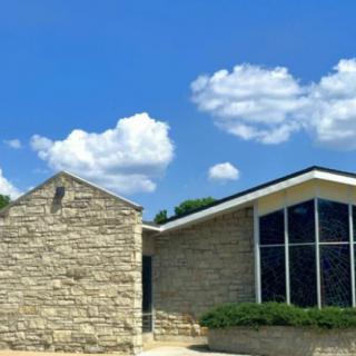 A modern stone building with large windows under a clear blue sky.