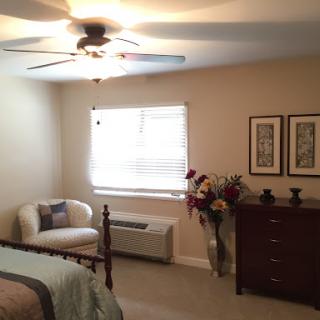 A cozy and well-decorated bedroom featuring a ceiling fan, comfortable seating, and decorative accents.