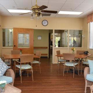 A dining room setup with tables, chairs, a ceiling fan, and a wall clock.