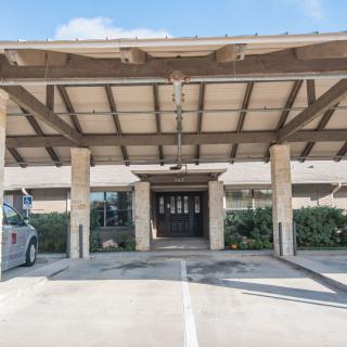 Covered entrance of a building with stone columns and wooden awning.