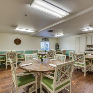 A spacious and well-lit dining area with neatly arranged tables and chairs, featuring a warm wooden floor.