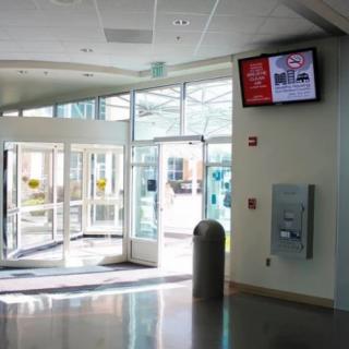 A modern lobby entrance with glass doors and a wall-mounted television screen.