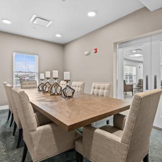 A modern meeting room featuring a spacious wooden conference table surrounded by comfortable upholstered chairs, designed for professional gatherings.