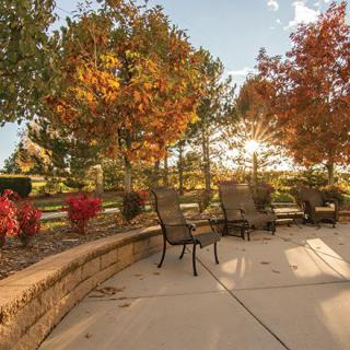 A cozy patio surrounded by stunning autumn foliage, capturing the warm hues of fall at sunset.