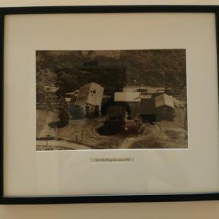 A serene black and white photograph depicting rural buildings surrounded by nature.