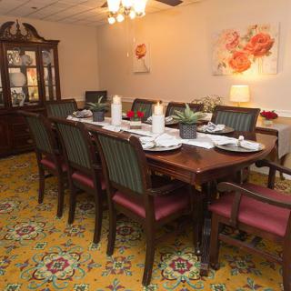 A well-decorated dining room with a large table set for dinner, surrounded by elegant chairs and adorned with a chandelier and artwork.