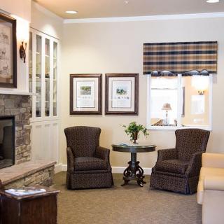 A cozy living room with two chairs, a fireplace, and decorative artwork on the wall.