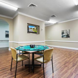 A spacious game room with a poker table and chairs on a hardwood floor, adorned with artwork on the walls.