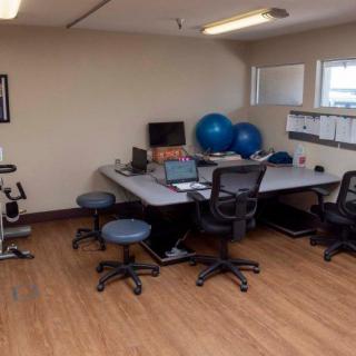A neat and organized office space with desks, chairs, and exercise equipment.