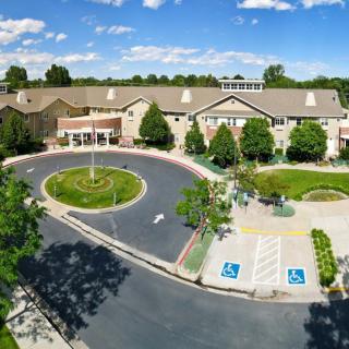 Aerial view of a large building with a circular driveway and surrounding greenery.