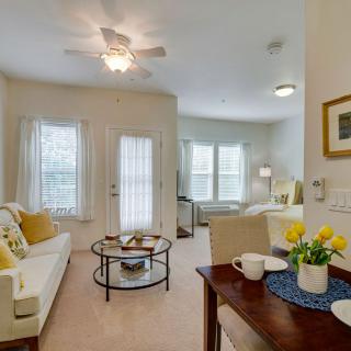 A cozy living room with elegant decor, featuring a comfortable sofa and coffee table, illuminated by natural light through large windows.