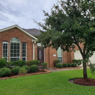 A suburban brick house with a well-maintained front yard and tree.