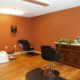 An interior view of a hair salon featuring chairs, a sink, and a wooden floor.