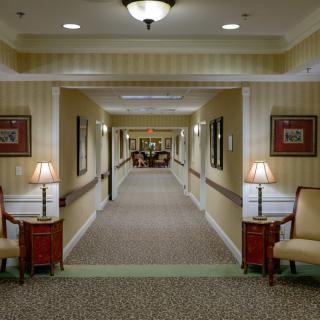 A well-lit hallway with chairs and lamps along the walls.