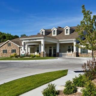 A modern residential building with a landscaped garden and driveway.