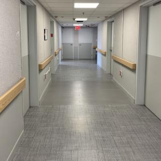 A view of a hospital hallway with doors leading to patient rooms.