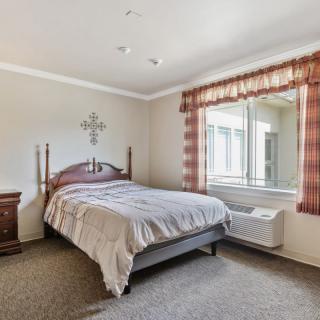A cozy bedroom with a bed, nightstand, and a window with plaid curtains.