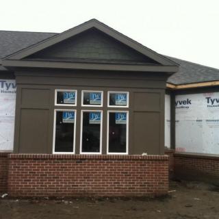 A house under construction with new windows and a partially completed brick exterior.
