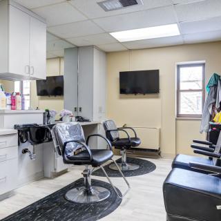 A modern salon interior with styling chairs, mirrors, and televisions.